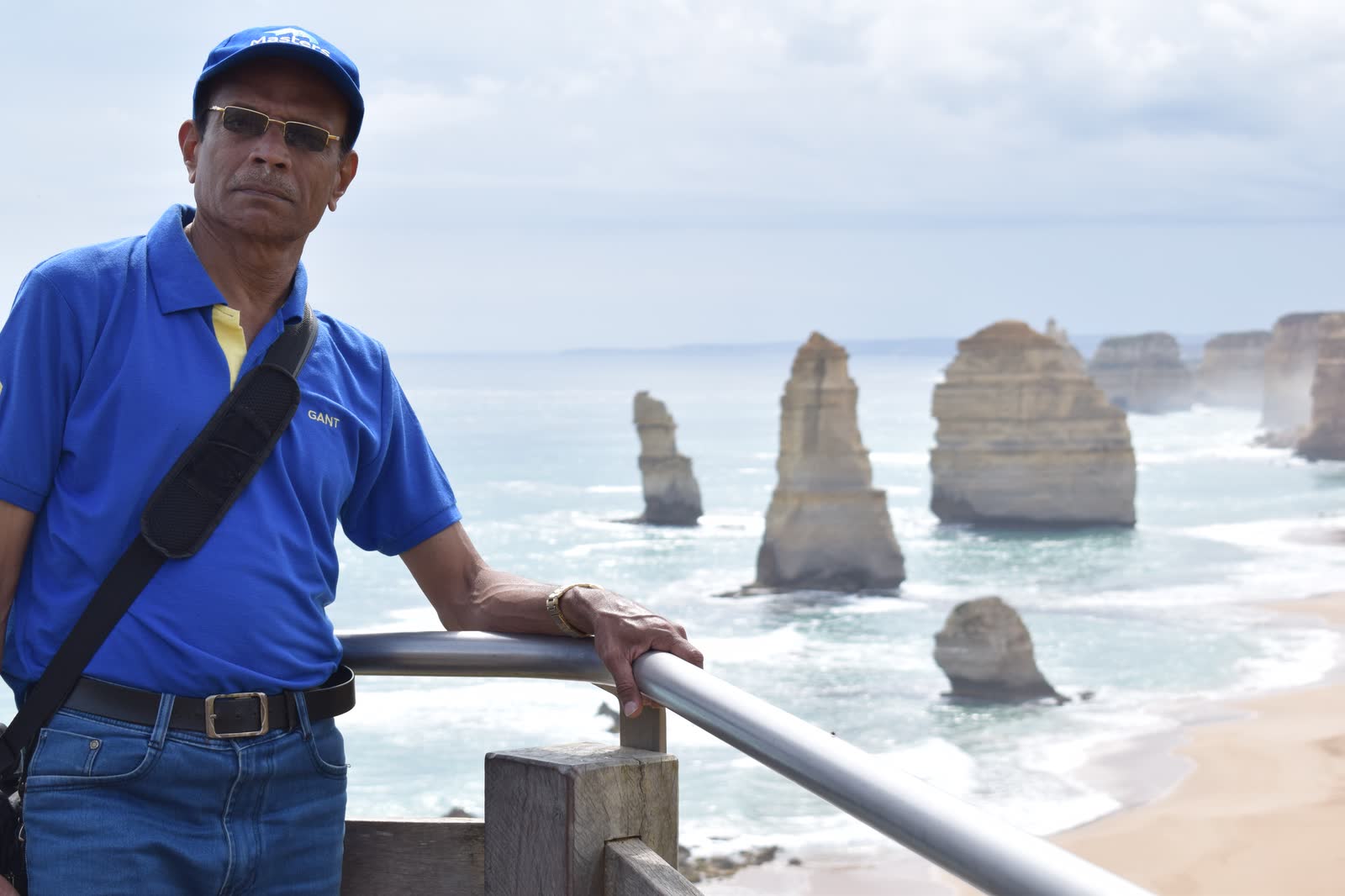 At a lookout rail above the sea, with tall limestone stacks standing in the surf behind.