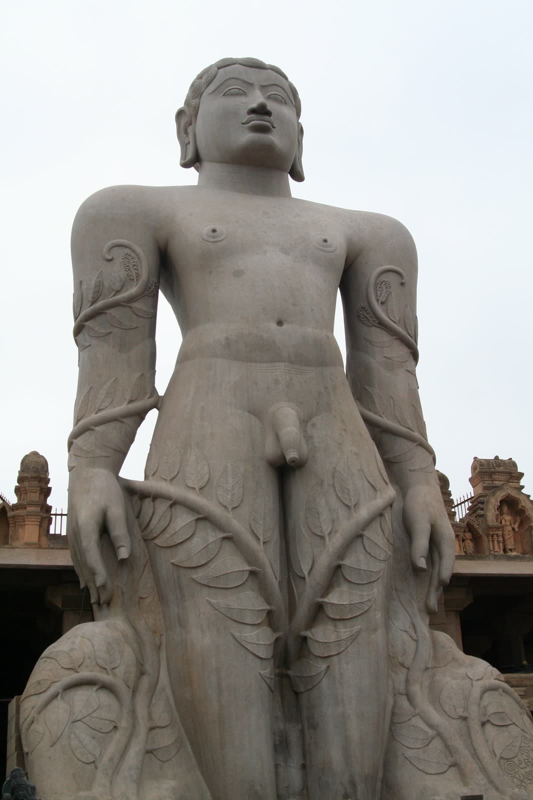 The Gommateshwara statue on Vindhyagiri hill at Shravanabelagola, carved from a single rock, seen from below against a pale sky.